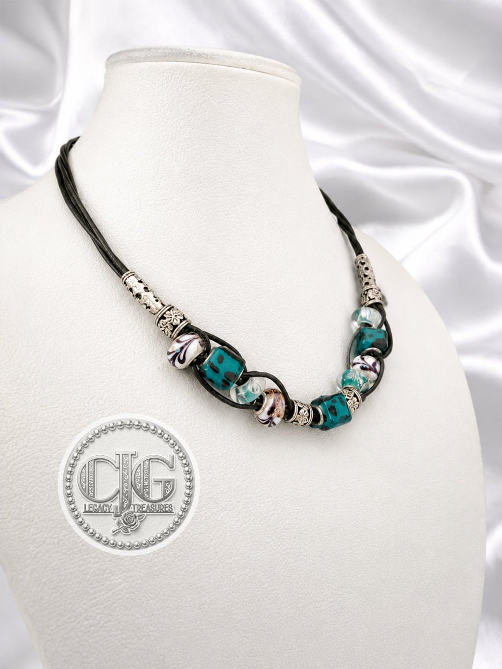 Teal leopard lampwork leather necklace displayed on white satin mannequin