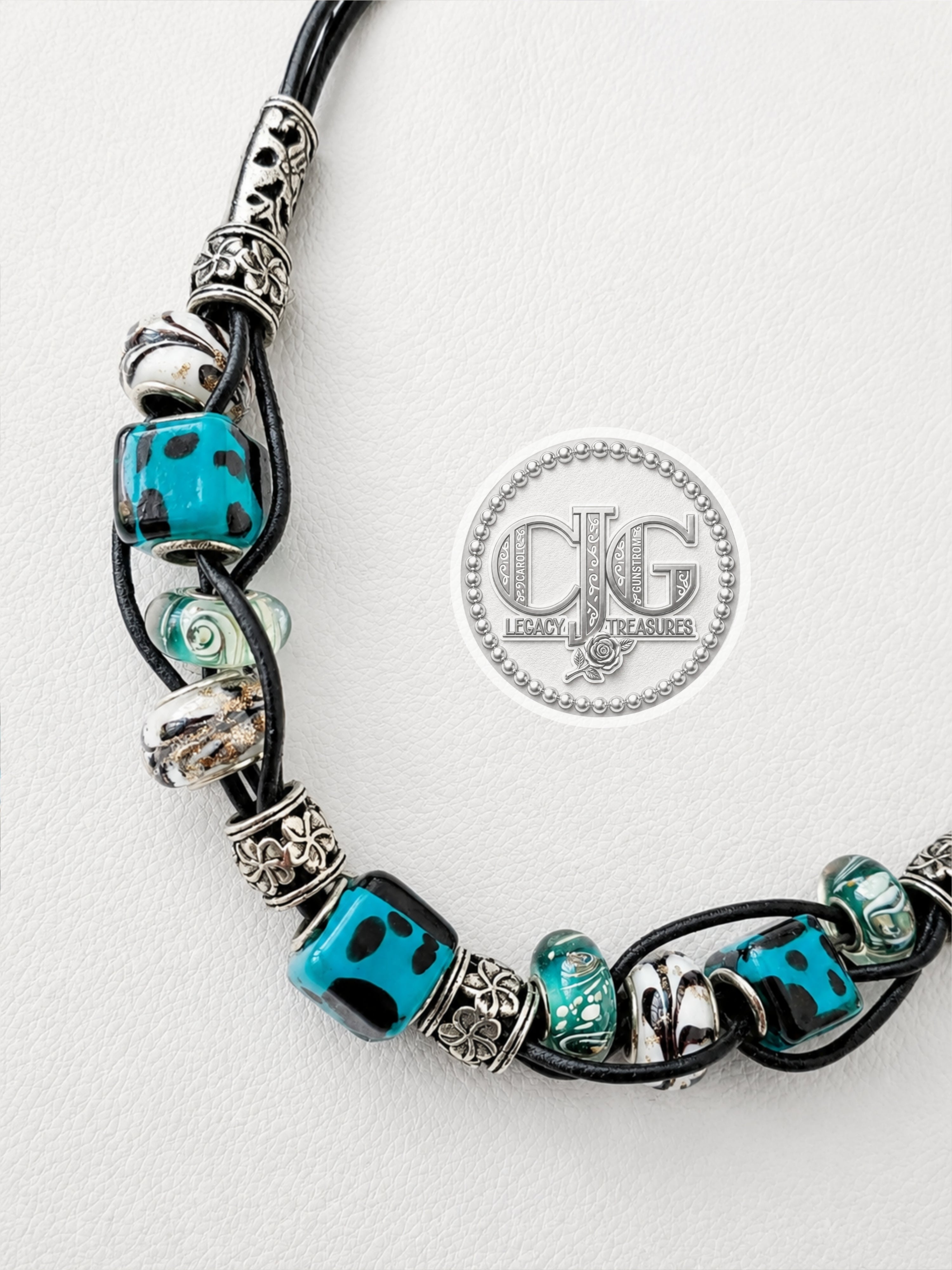 Close-up of teal lampwork and silver spacer beads on woven leather necklace